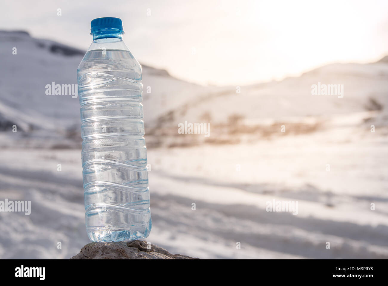 Water bottle with snowy mountain peak background. Stock Photo
