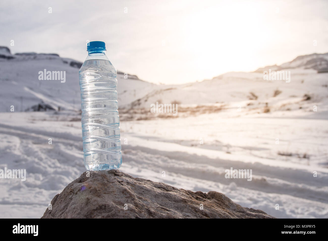 Water bottle with snowy mountain peak background. Stock Photo