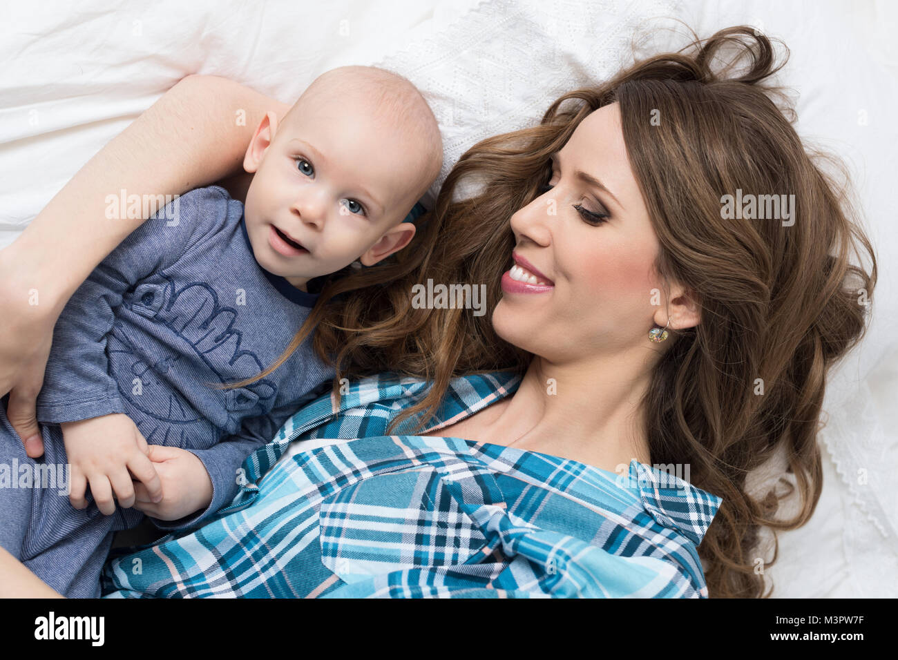 Happy mother and her baby son lying on a bed together. Happy family. Mother and newborn child portrait. Stock Photo