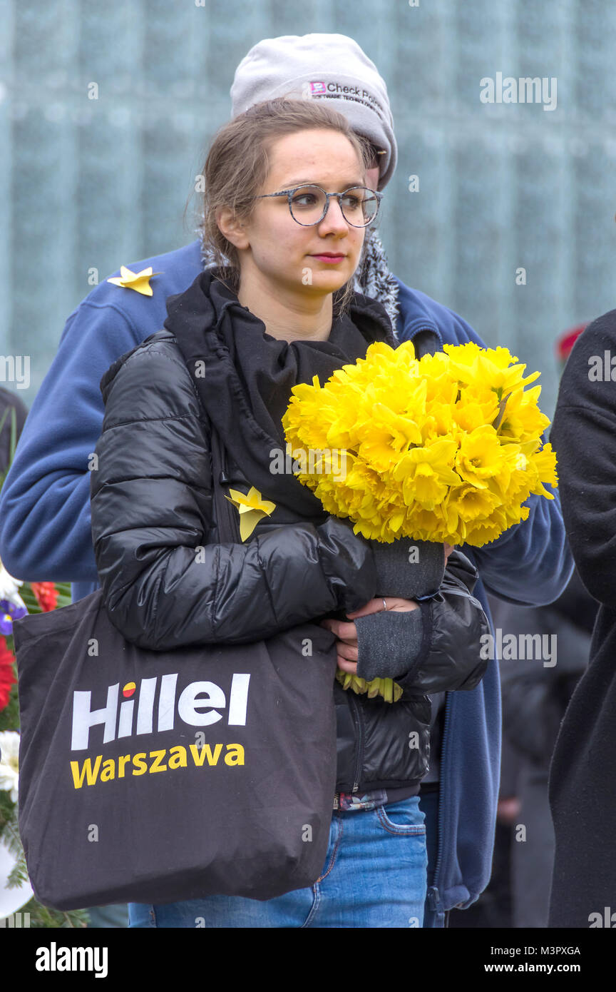 Warsaw, Poland - April 19, 2017: Young woman holds a bouquet of yellow daffodils during a ceremony at the Warsaw Ghetto Heroes Monument. Stock Photo