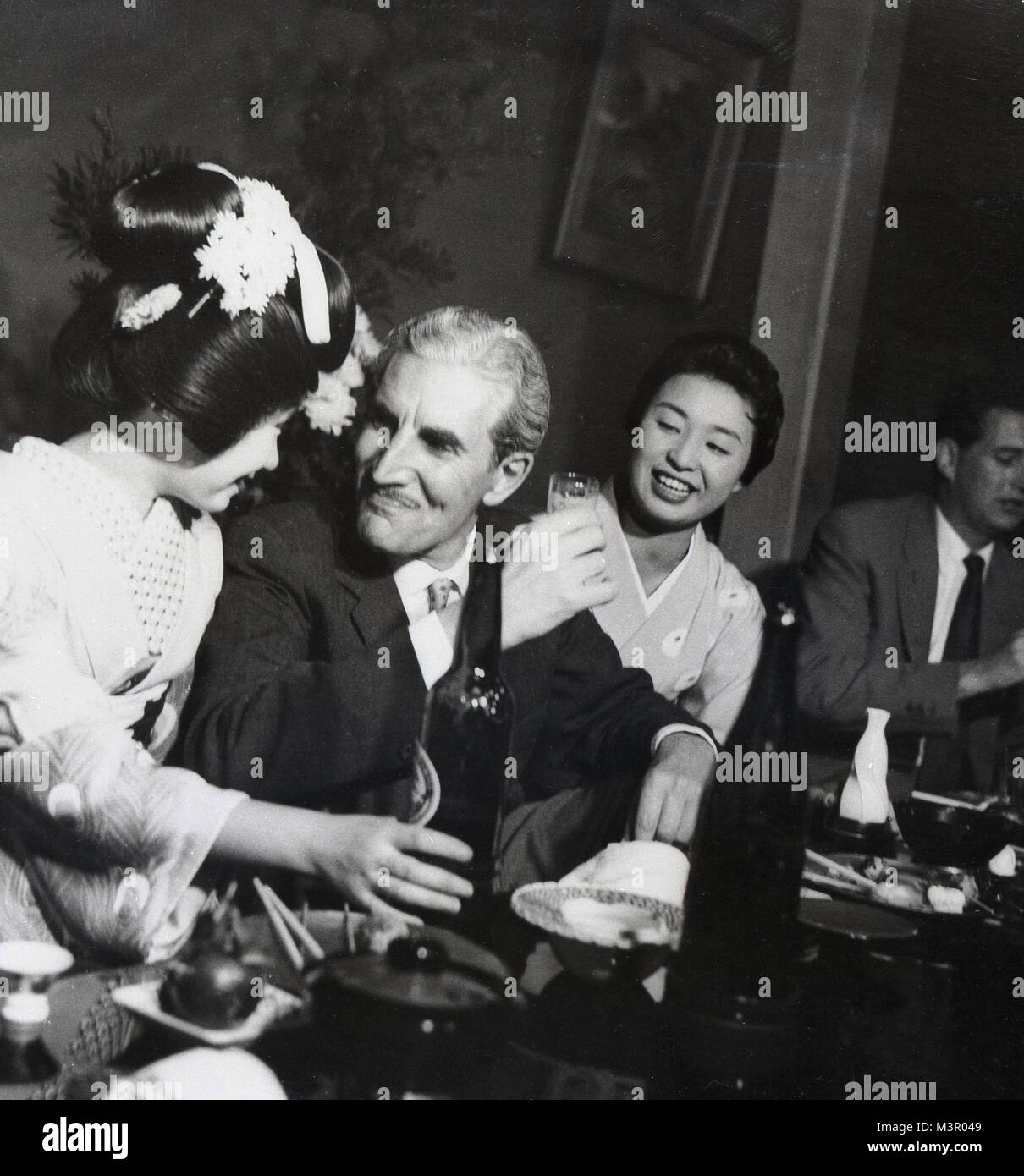 1950s, historical, a western gentleman being served a drink by a Japanese geisha girl in a hostess bar, Tokyo, Japan. Stock Photo