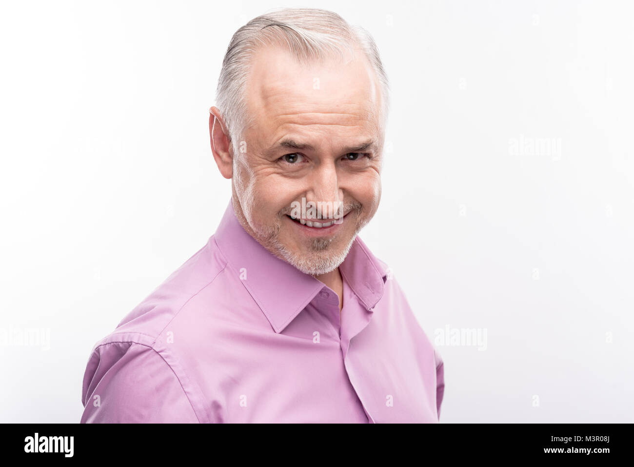 Handsome grey-haired man smiling cheekily while posing Stock Photo
