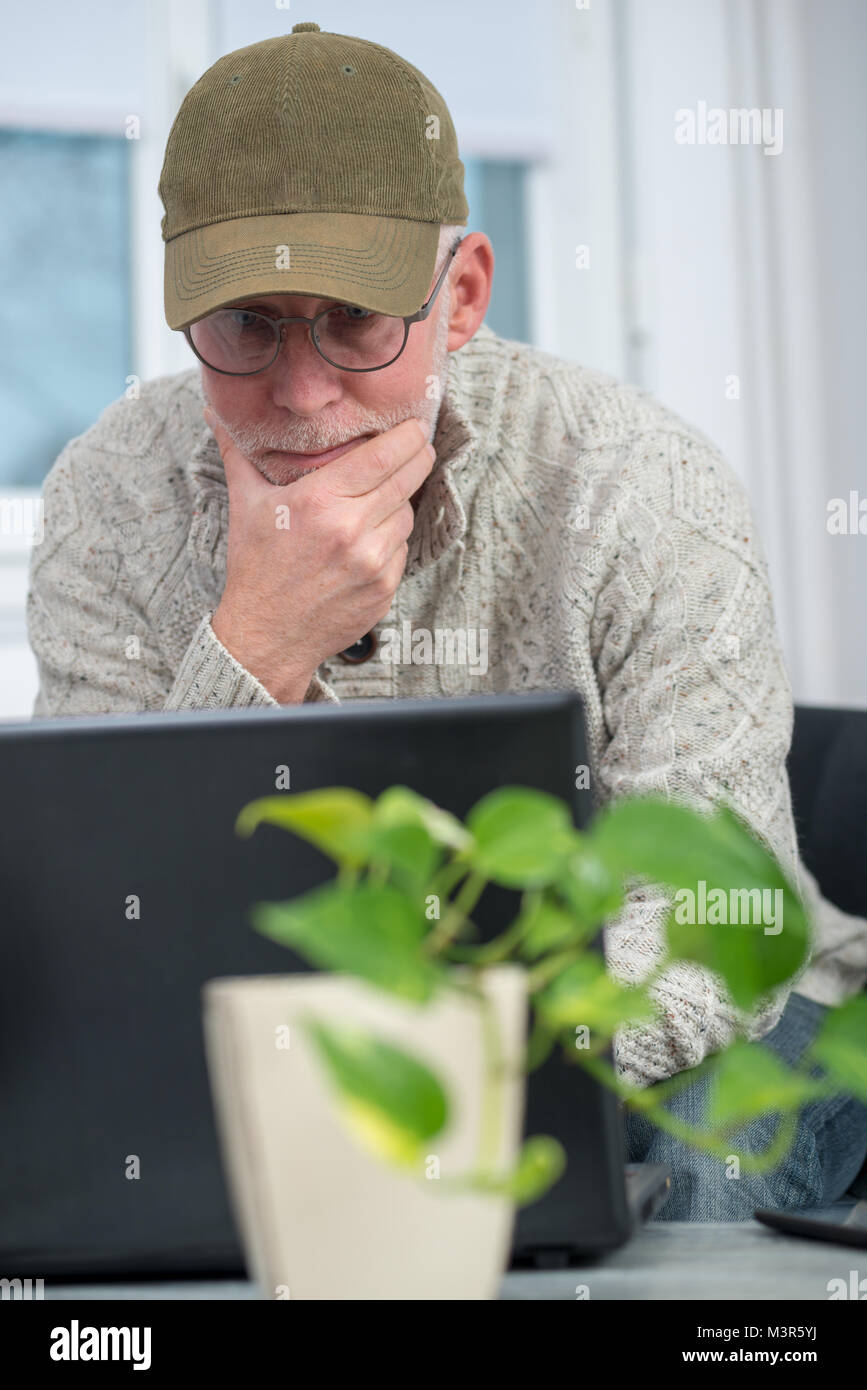 senior man with cap using a laptop at home Stock Photo - Alamy