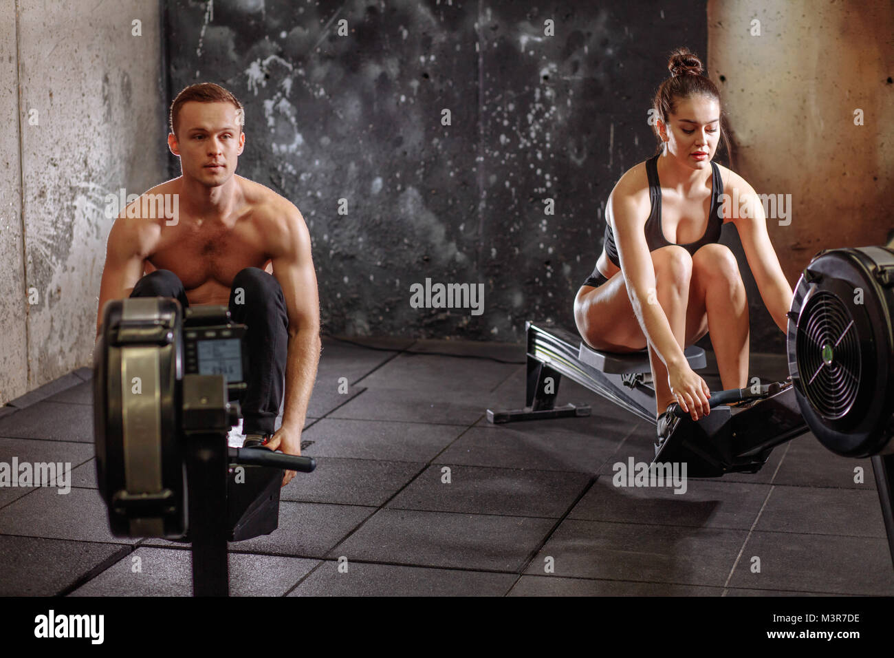 couple doing exercises with rowing machine Stock Photo