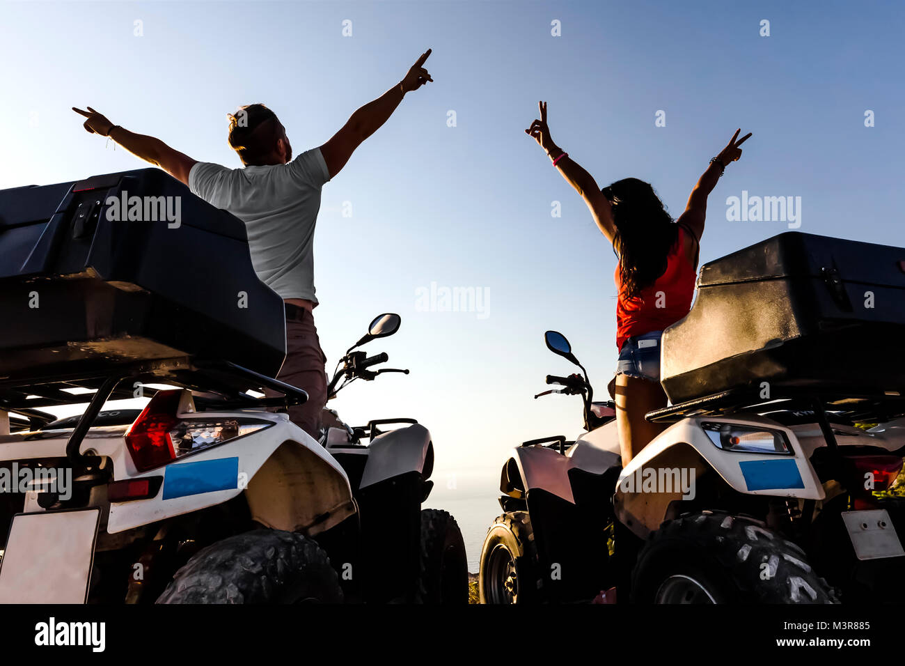 happy couple on quad bikes enjoying a trip on a sunset background, silhouette photo, rear view, Zante Stock Photo
