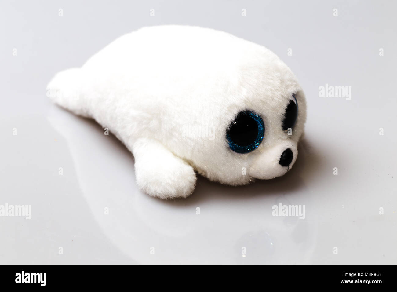 A white baby seal plush toy with big blue eyes. Furry cute animal Stock