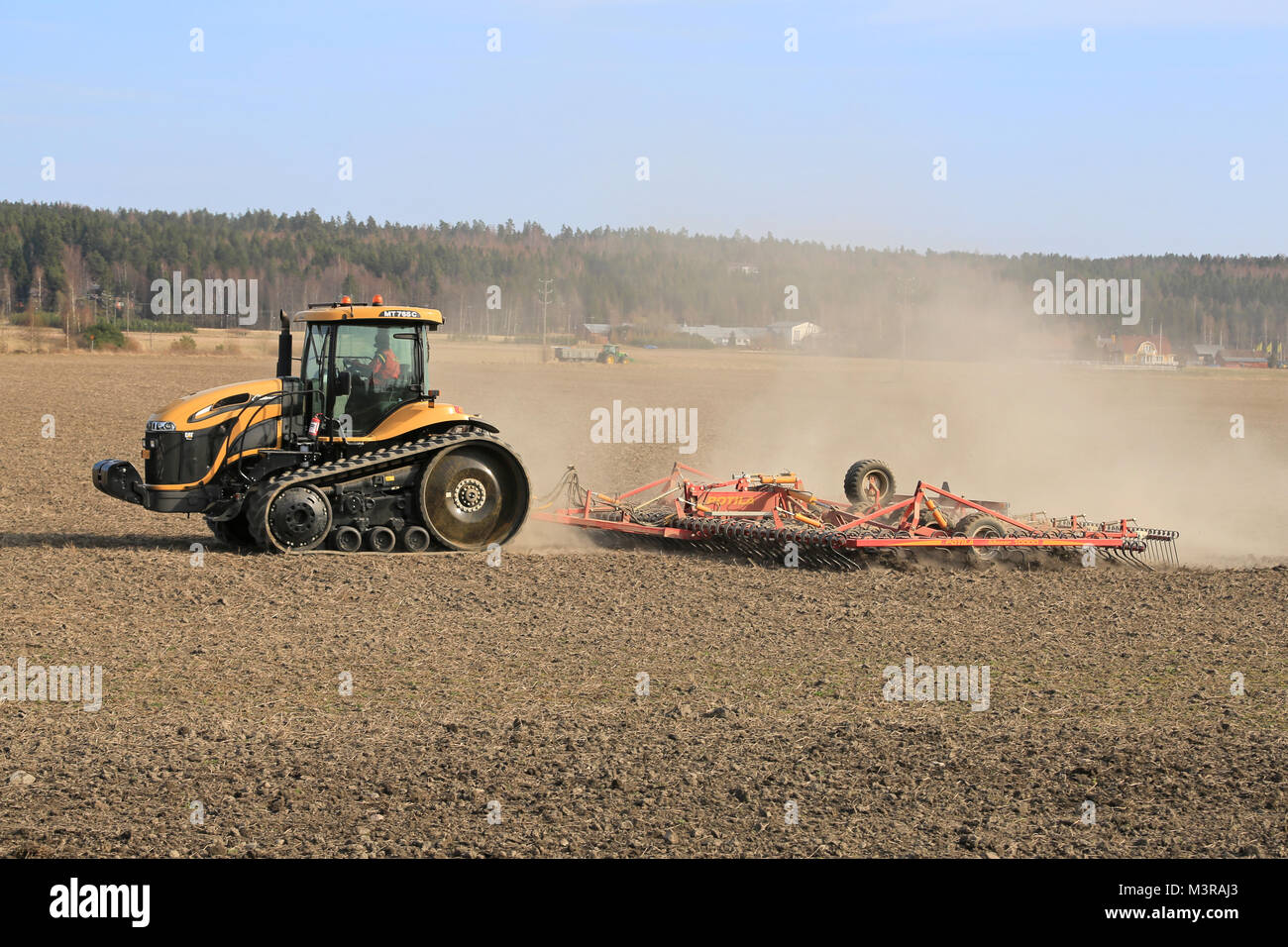 SALO, FINLAND - APRIL 19, 2014: Farmer cultivating field with Cat Challenge MT765c agricultural crawler tractor and seedbed cultivator.A crawler tract Stock Photo