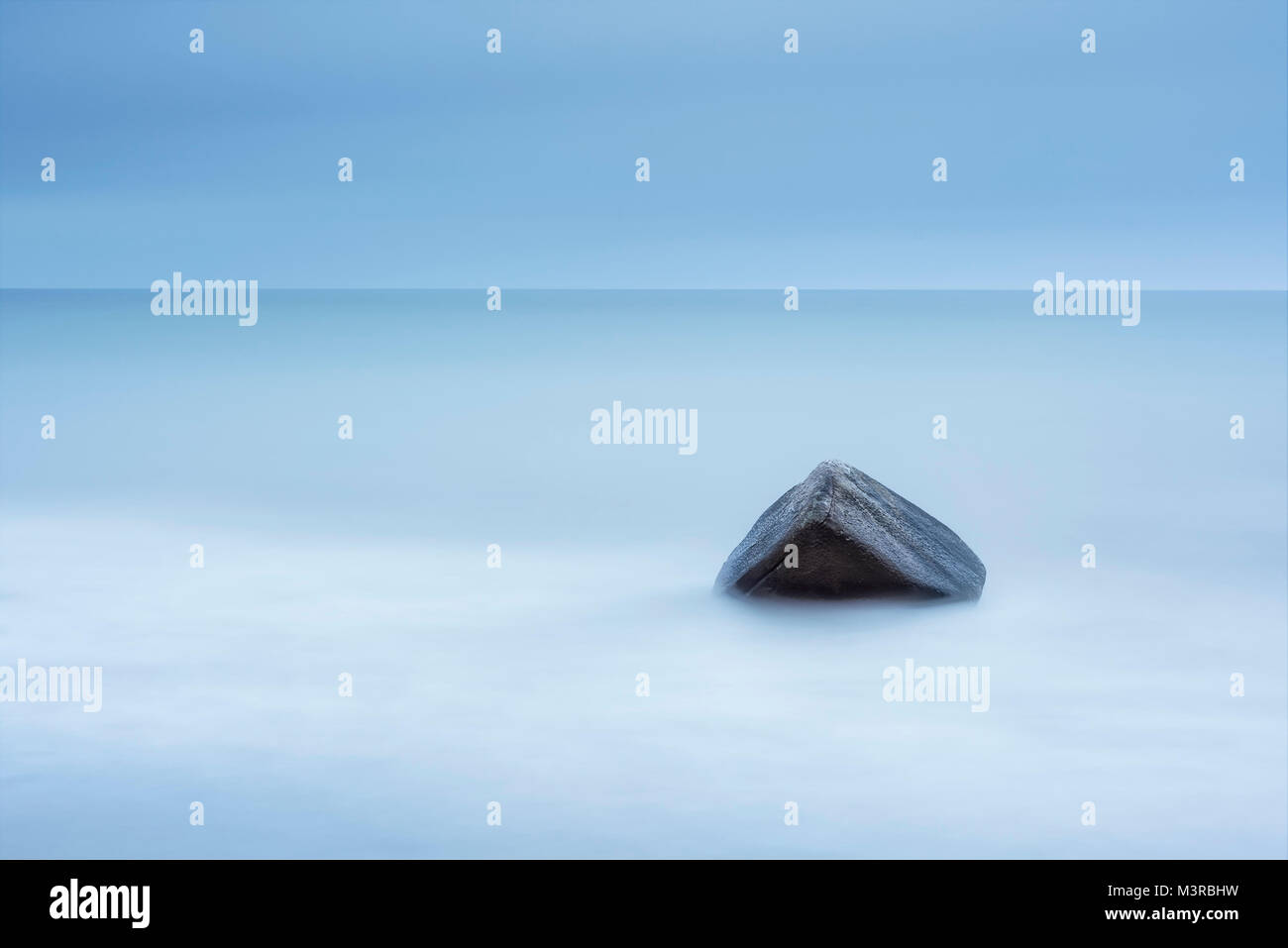 A very large boulder in a cloudy mist of waves. Long exposure. Stock Photo