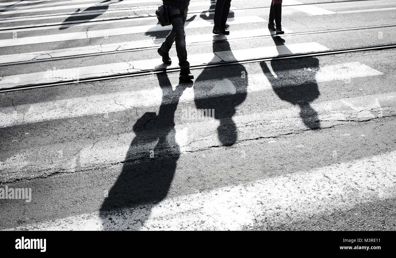 Shadow silhouette of a people crossing the street , in black and white ...