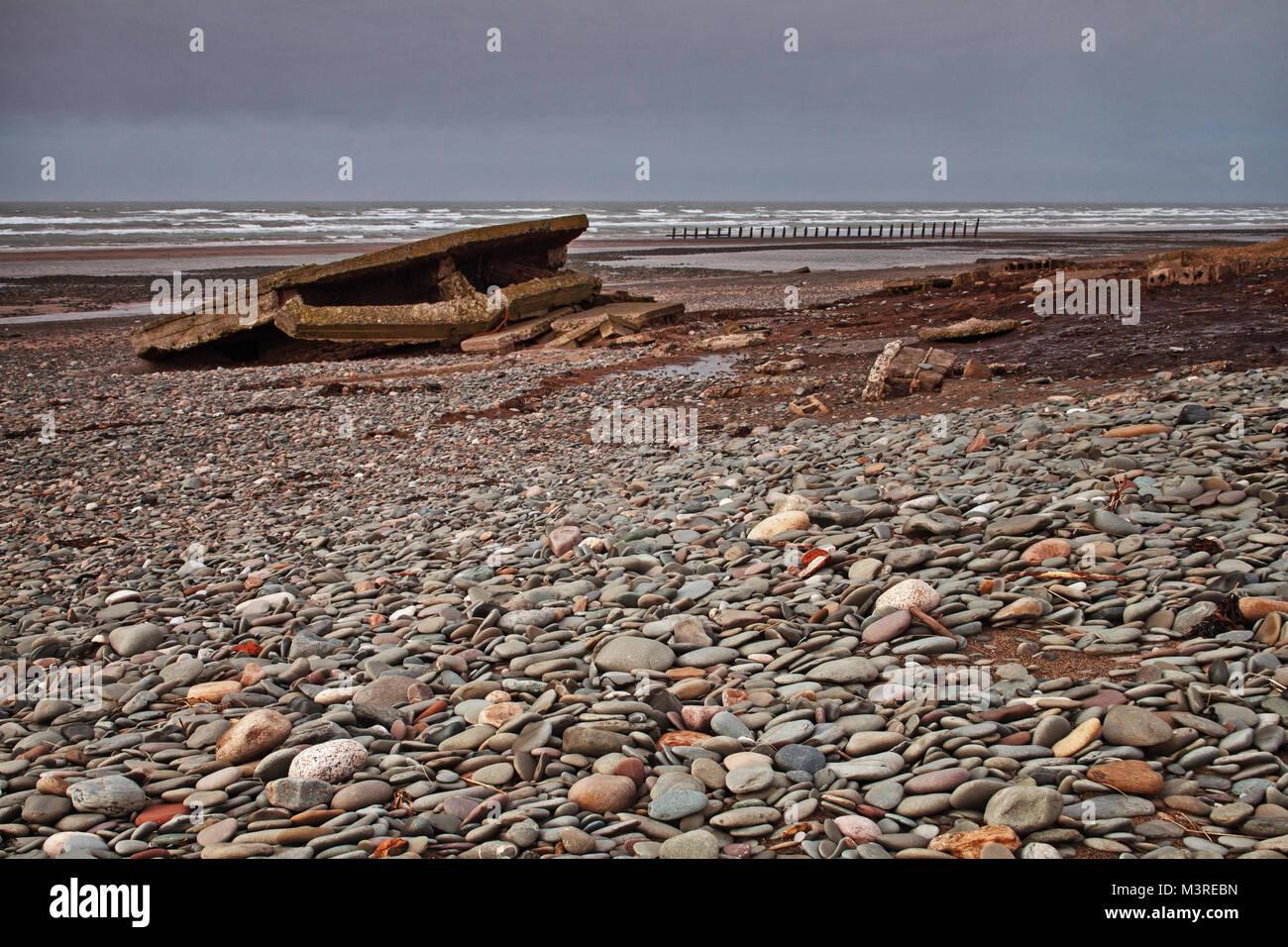 Remnants of war: a disused air raid shelter, broken and left on the beach at Walney Island, Barrow in Furness Stock Photo