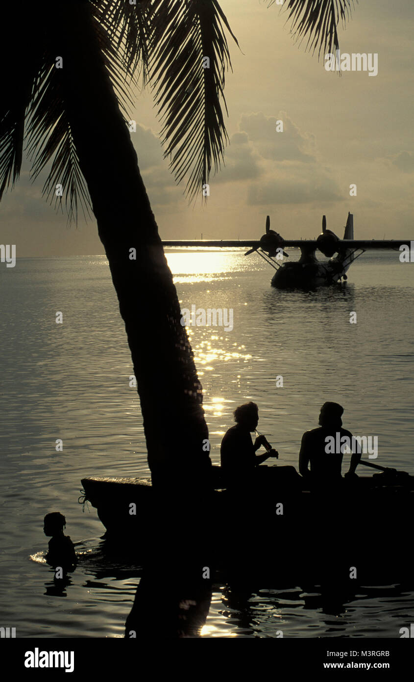 Brazil. Salvador de Bahia. Catalina PBY-5a  flying boat, hydroplane, from WOII. People having a drink on the boat and swimming at sunset. Stock Photo