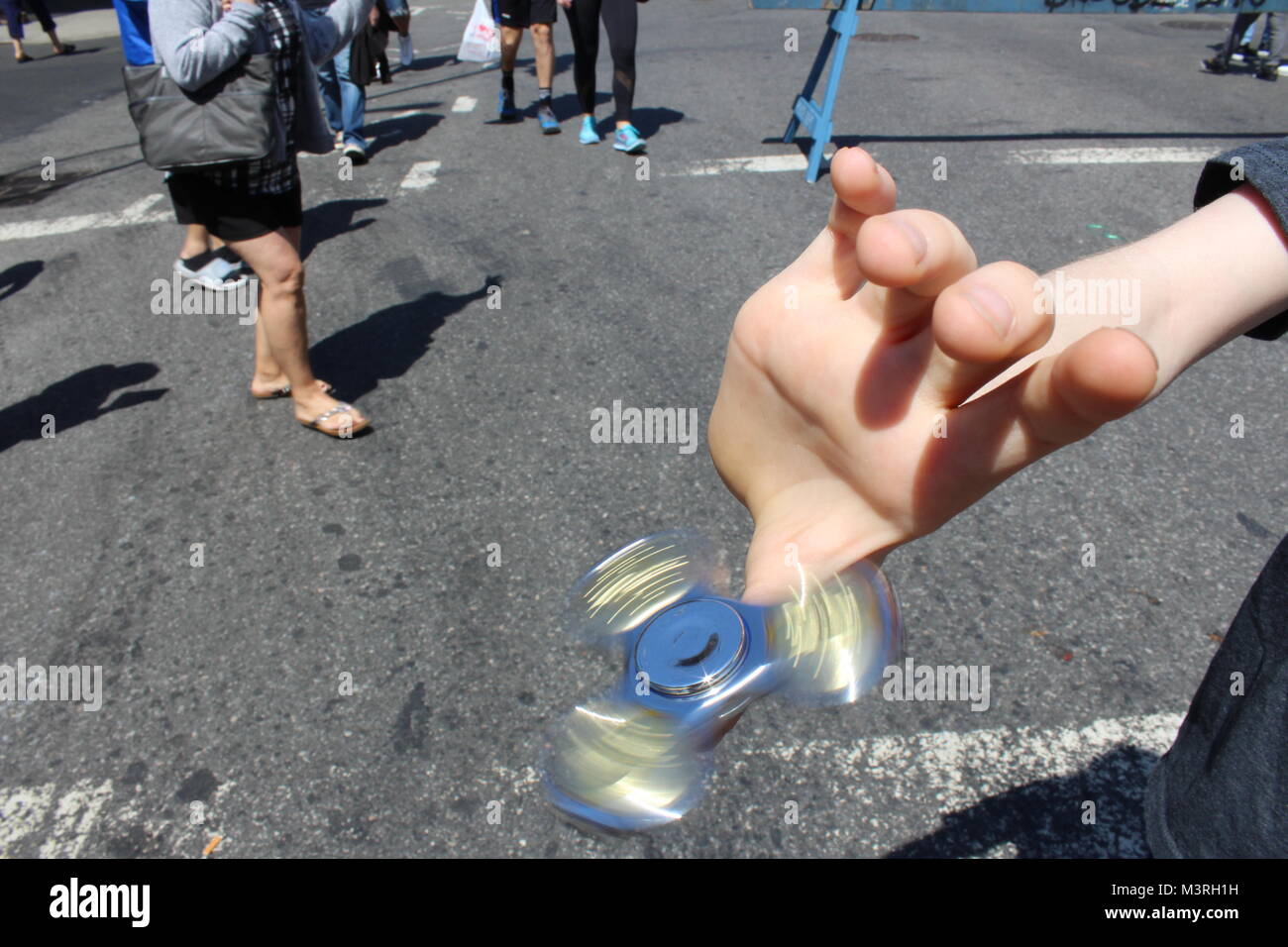 a child spins a fidget spinner on his thumb in  a brooklyn street new york USA Stock Photo