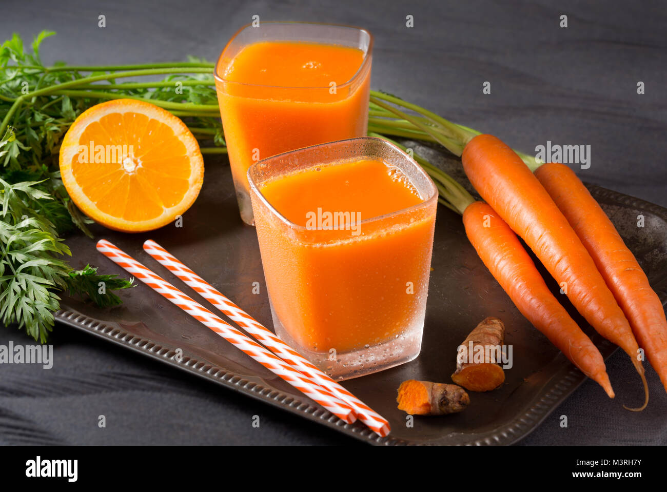 Two glasses of fresh carrot-orange juice with turmeric root Stock Photo