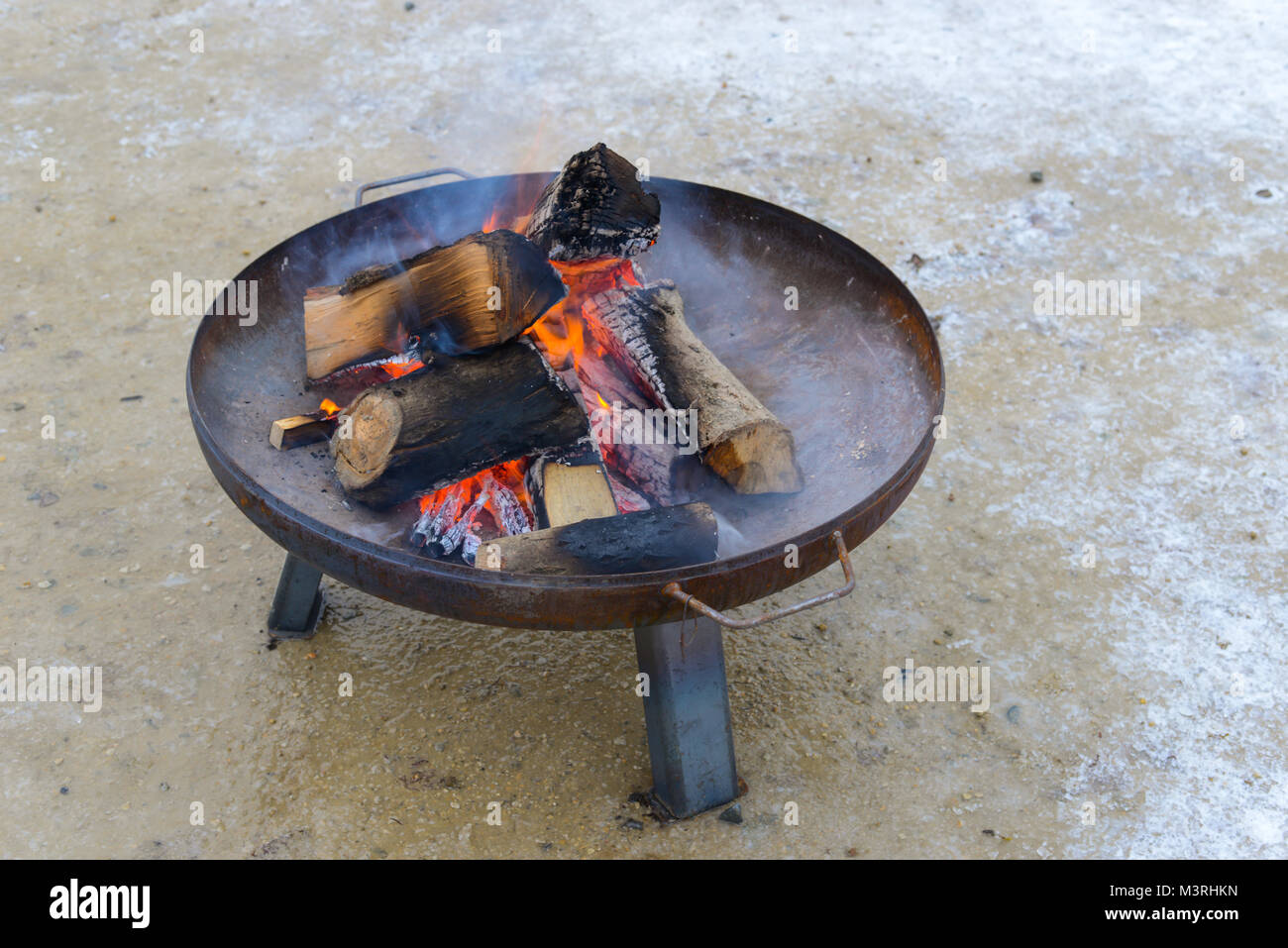 aereal view on a fire place with a metal bowl and burning wood. Stock Photo