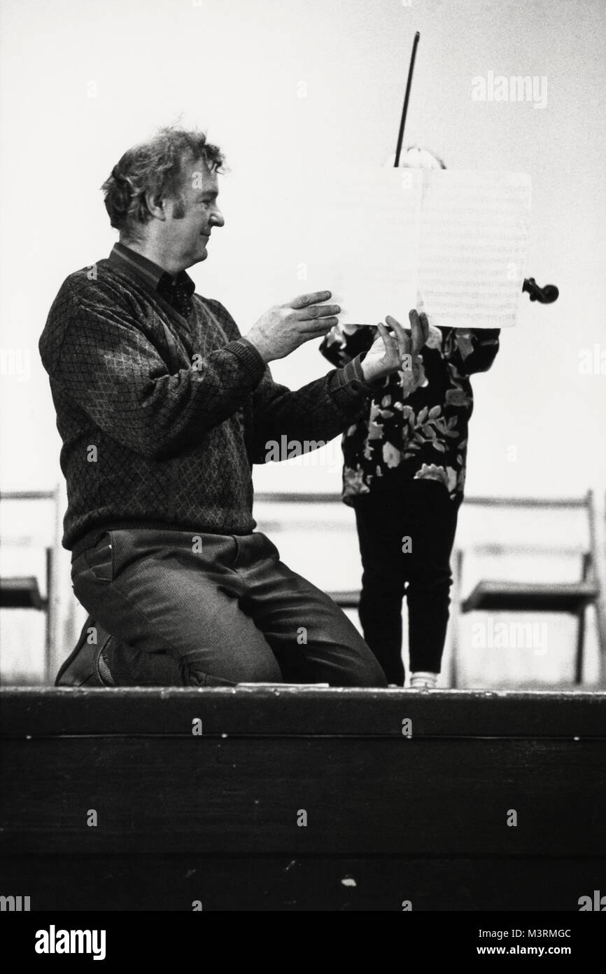 Young girl playing violin with sheet music held by man at small eisteddfod in village hall at Y Graig Dyfed Wales UK Stock Photo