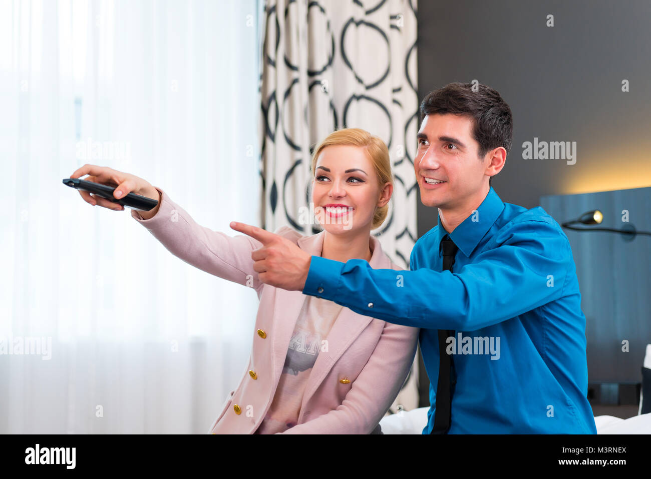 Couple switching TV with remote control in hotel room Stock Photo