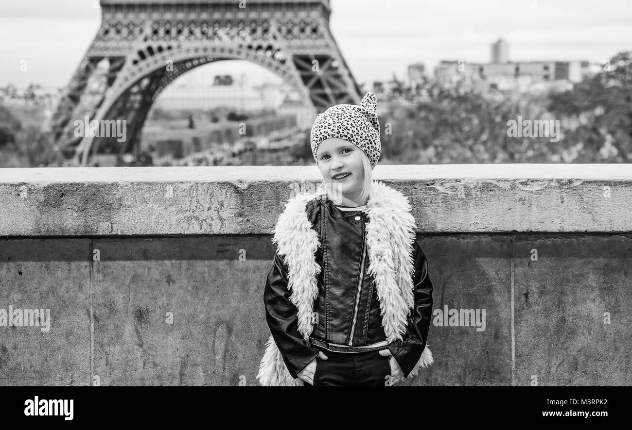 Bold Winter in Paris. Full length portrait of smiling trendy child in the front of Eiffel tower in Paris, France Stock Photo