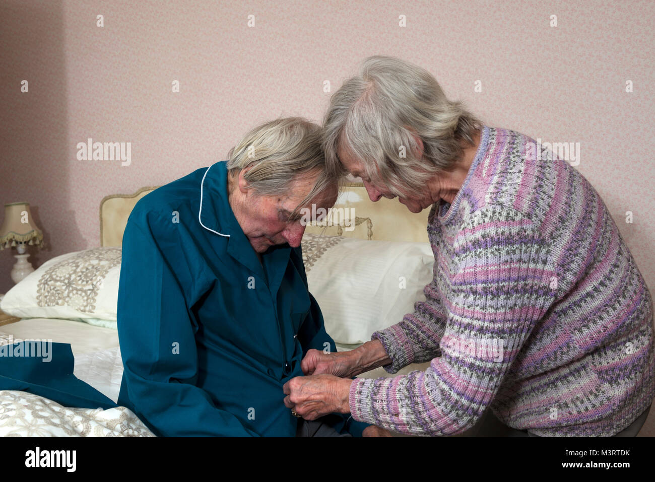 Sister helping elderly brother getting ready for bed Stock Photo