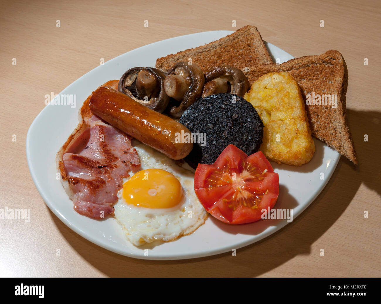 Full English breakfast of sausage, fried eggs, black pudding, tomato