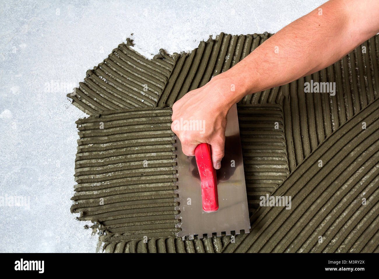 Worker hand with trowel tool for tiles installation making mortar