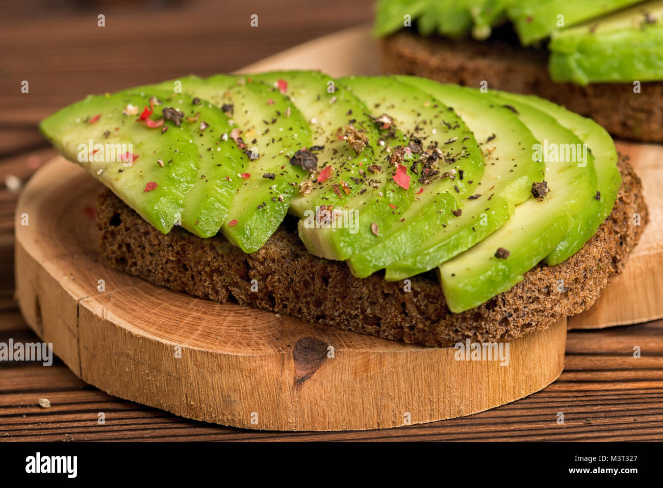 avocado sandwiches with rye bread toast and peppered on wooden background, healthy organic food concept Stock Photo