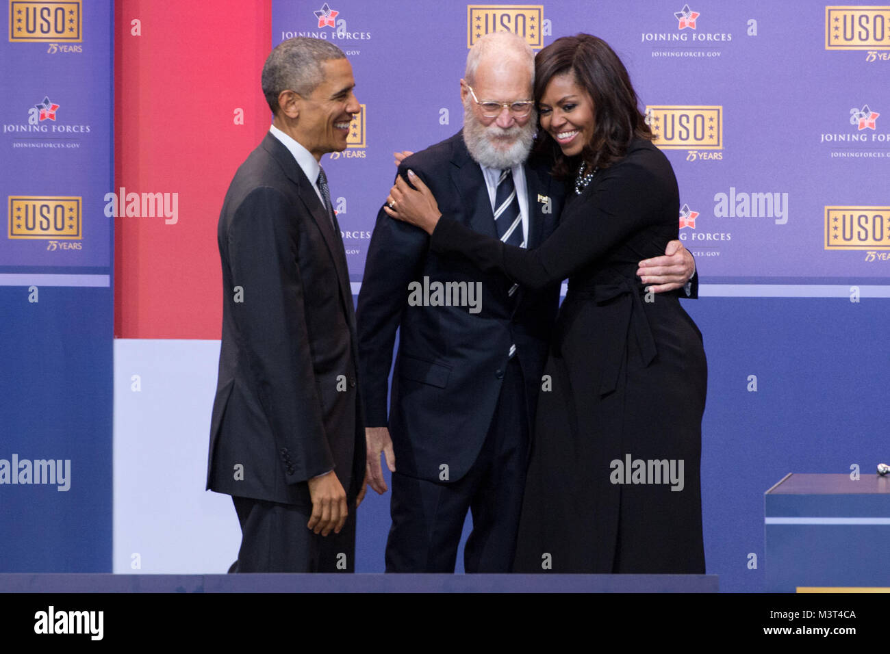 First Lady Michelle Obama hugs former Late Show Host David Letterman as President Barack Obama looks on during the comedy show in celebration of the 75th anniversary of the USO and the 5th anniversary of Joining Forces at Joint Base Andrews in Washington, D.C. May 5, 2016. Joining Forces is an initiative to help military, veterans and their families founded by Dr. Jill Biden and First Lady Michelle Obama. (DoD News photo by EJ Hersom) 160505-D-DB155-003 by DoD News Photos Stock Photo