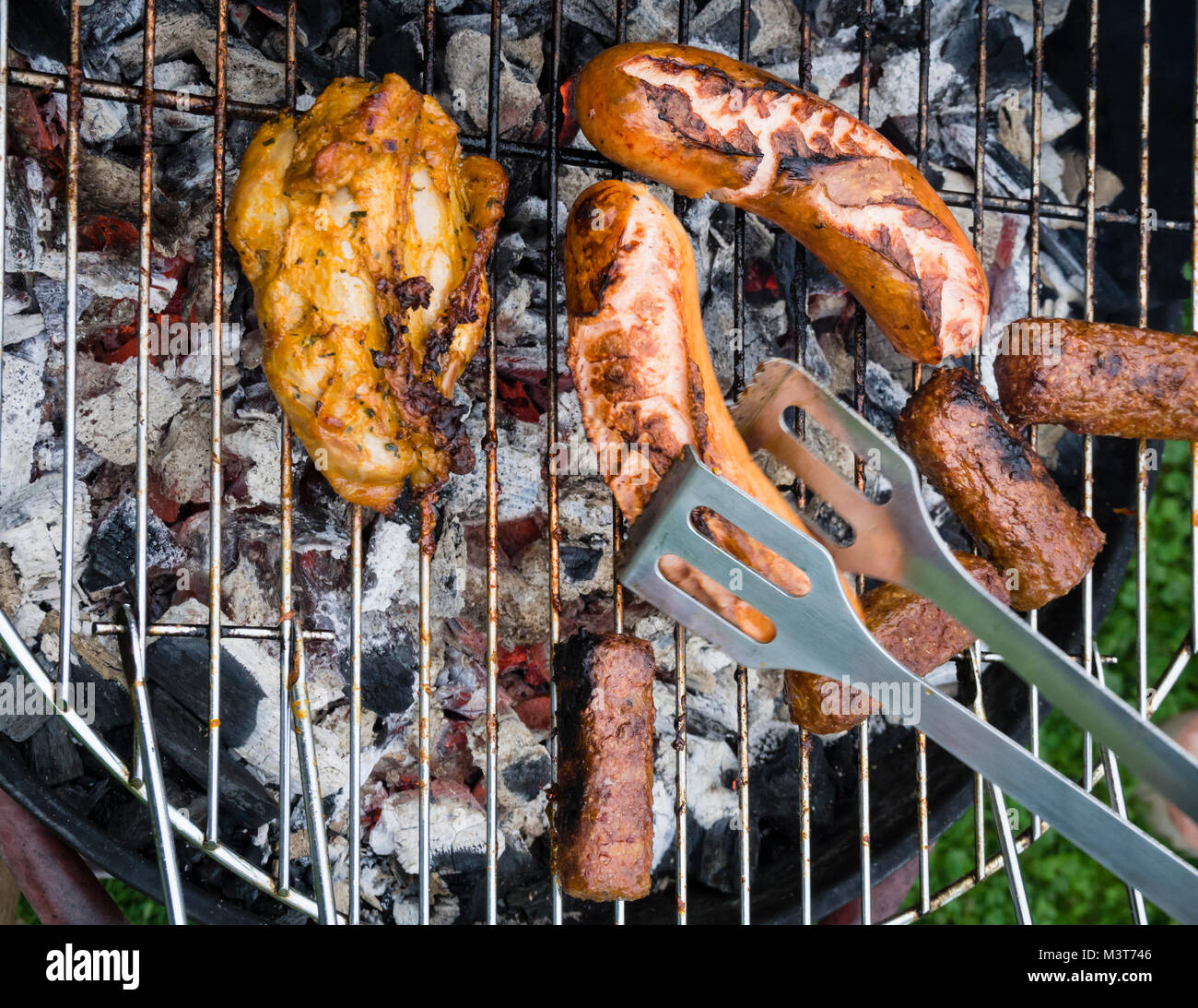 View from above onto a variety of roast meat and sausages on a barbecue