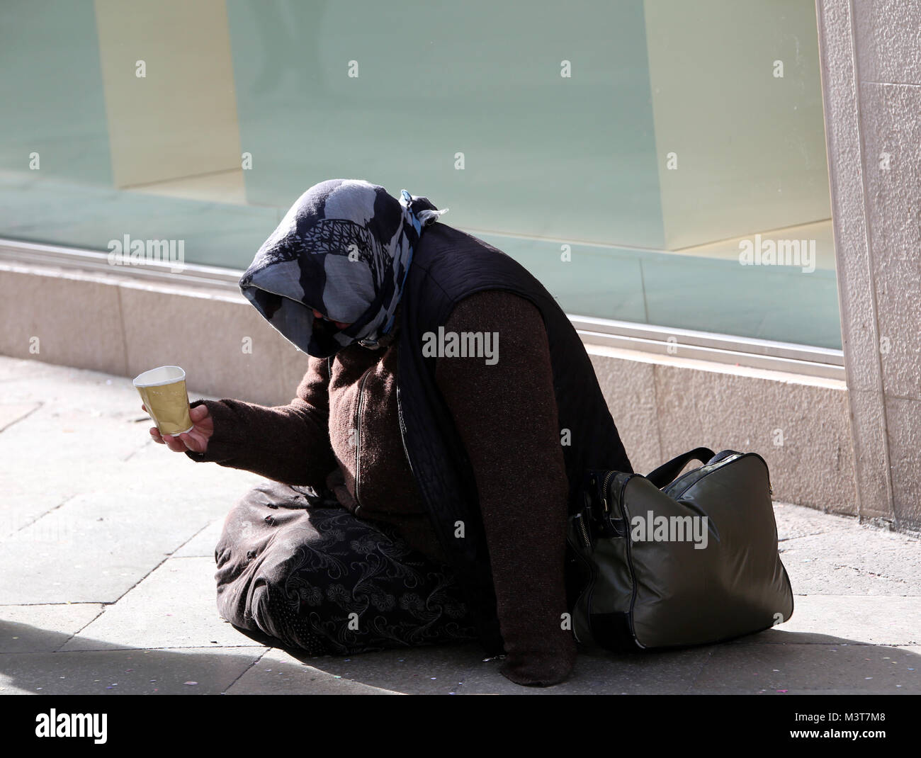 elderly poor Gypsy woman begs for alms lying in the street Stock Photo ...