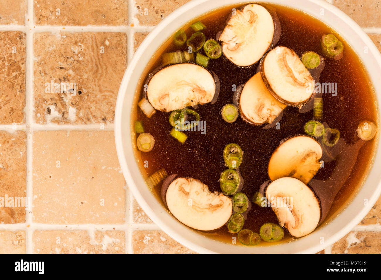 Bowl Of Japanese Style Clear Onion Soup With Mushrooms and Spring