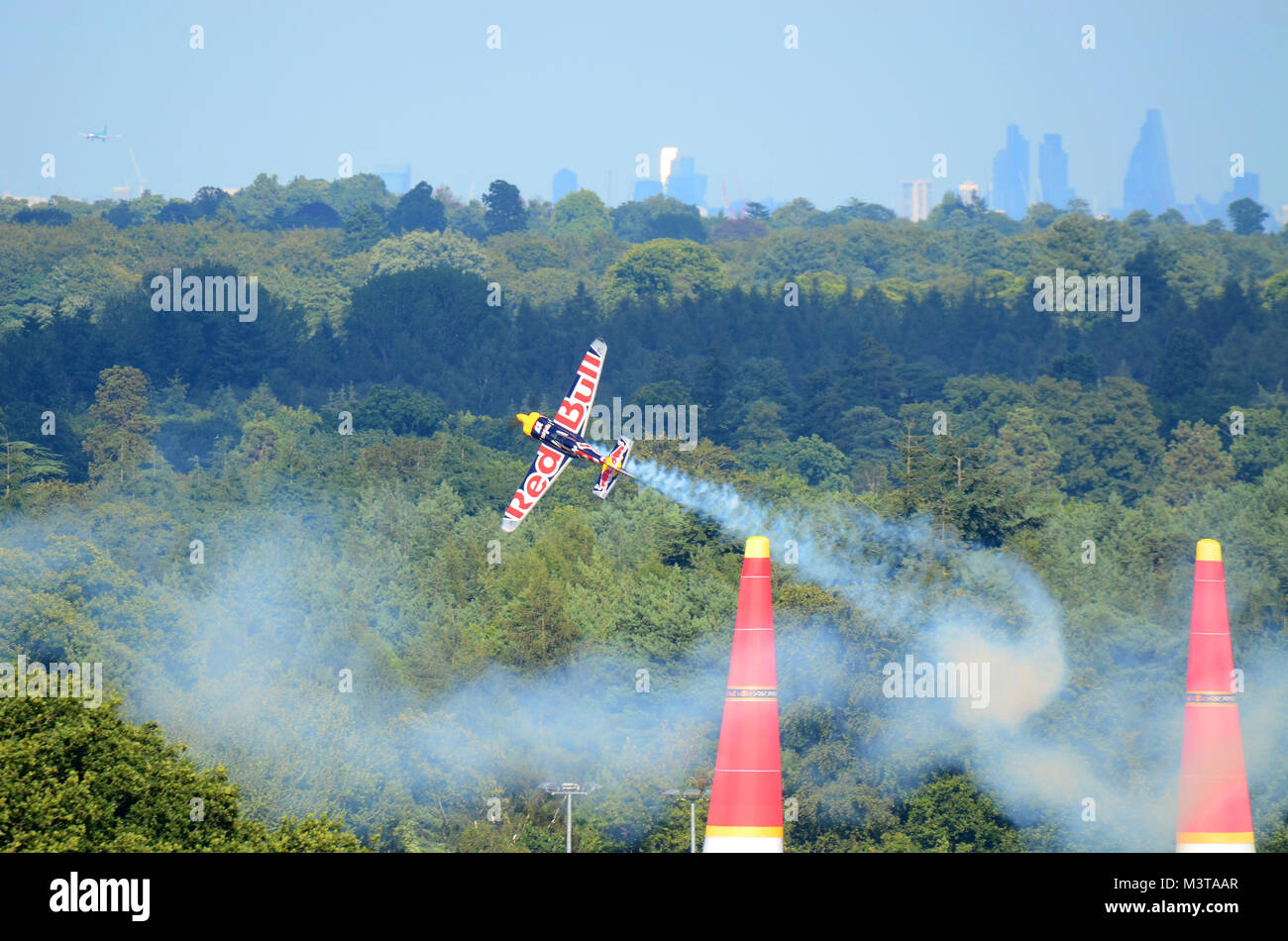 Pilot competing in the Red Bull Air Race Royal Ascot Racecourse race course flying over the Royal Berkshire countryside with London city skyline Stock Photo