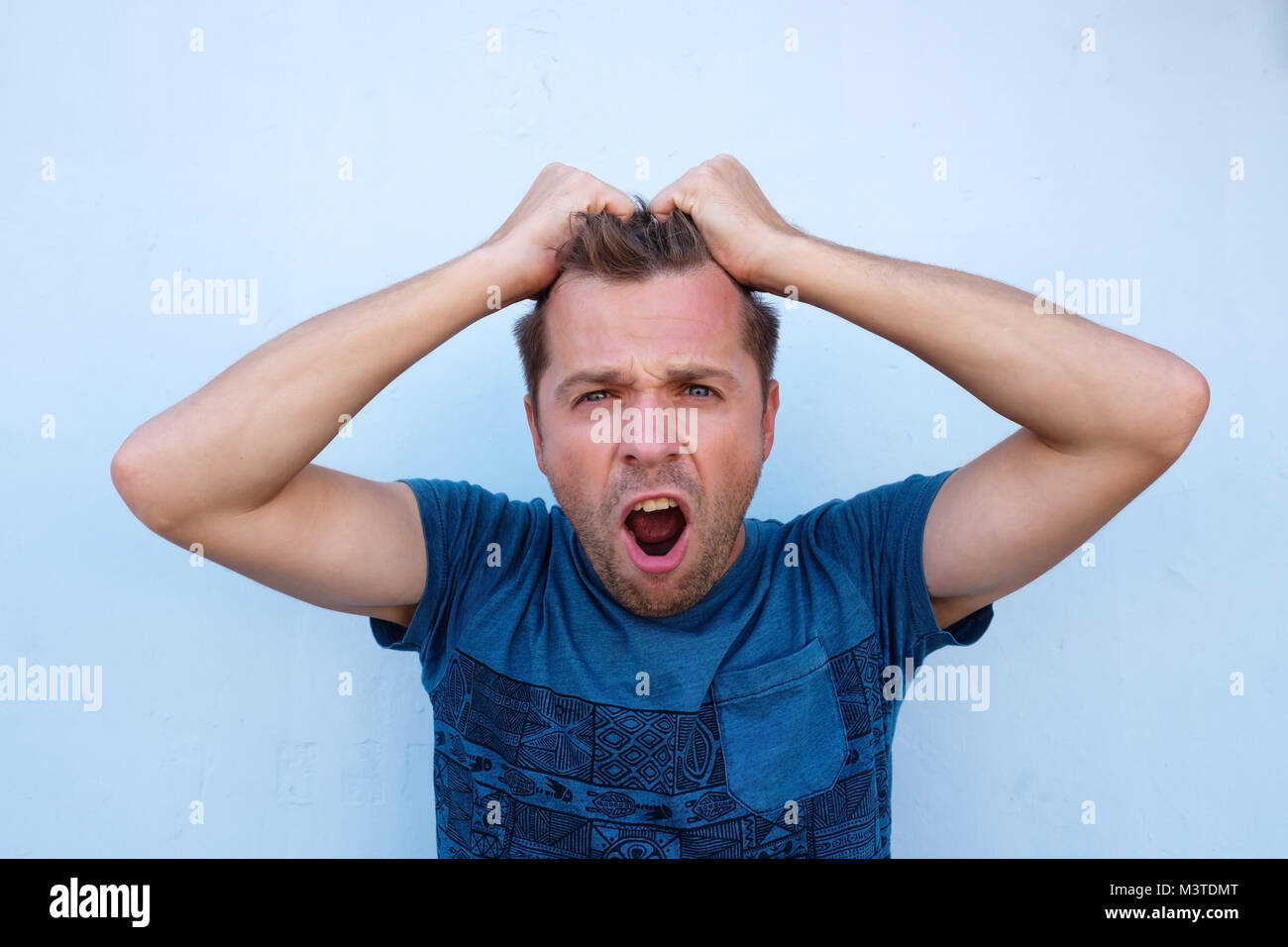 Desperate caucasian man holding his head. He is totally shocked with news he got Stock Photo