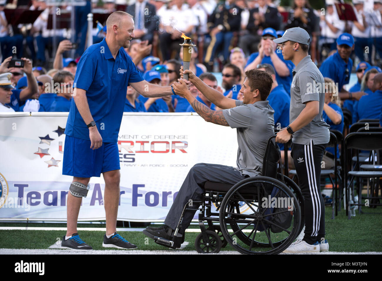 Retired Air Force Capt. Chris Cochrane, left, accepts the 2016 Department of Defense Warrior Games torch from Navy Lt. Ramesh Haytasingh of the Special Operations Command team during opening ceremonies at the U.S. Military Academy in West Point, N.Y. June 15, 2016. With Haytasingh is his son Tobias. (Department of Defense photo by EJ Hersom) 160615-D-DB155-010 by DoD News Photos Stock Photo