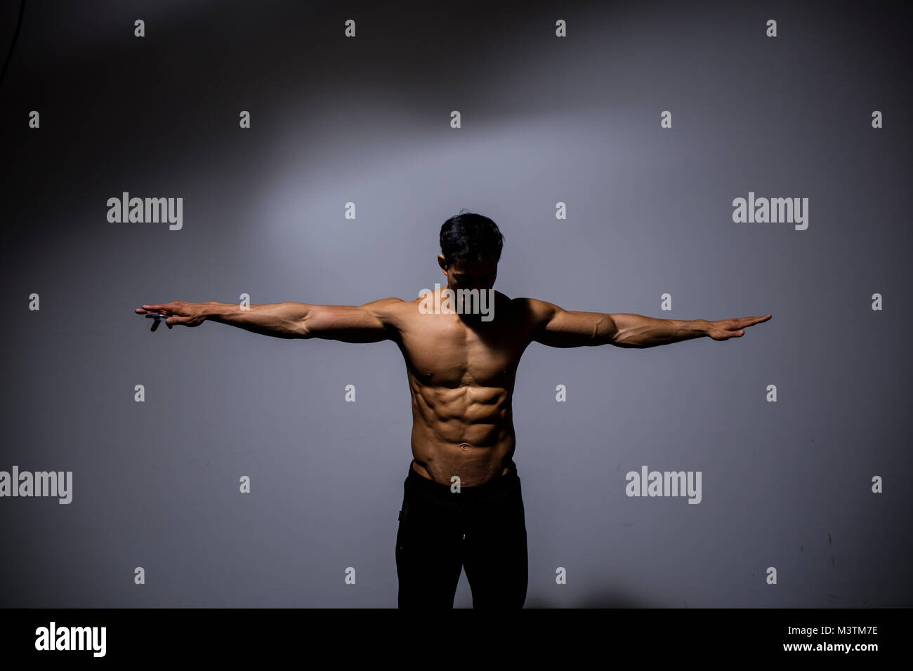 A male fitness model shows wingspan. Arms stretched out. Medium shot