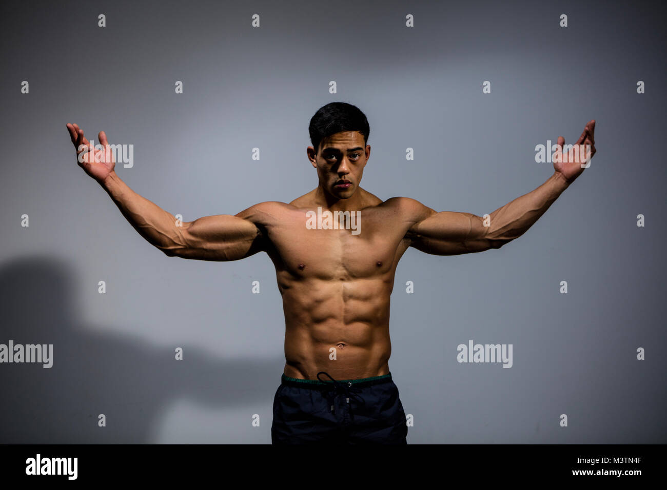 An Asian fitness model displays his biceps and pectoral muscles by stretching  out his arms Stock Photo - Alamy