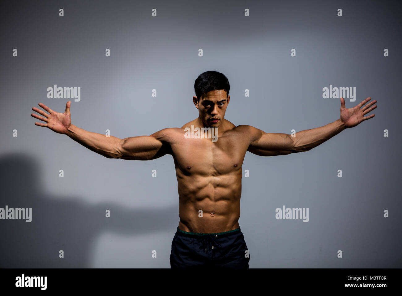 An Asian fitness model displays his biceps and pectoral muscles by stretching  out his arms Stock Photo - Alamy