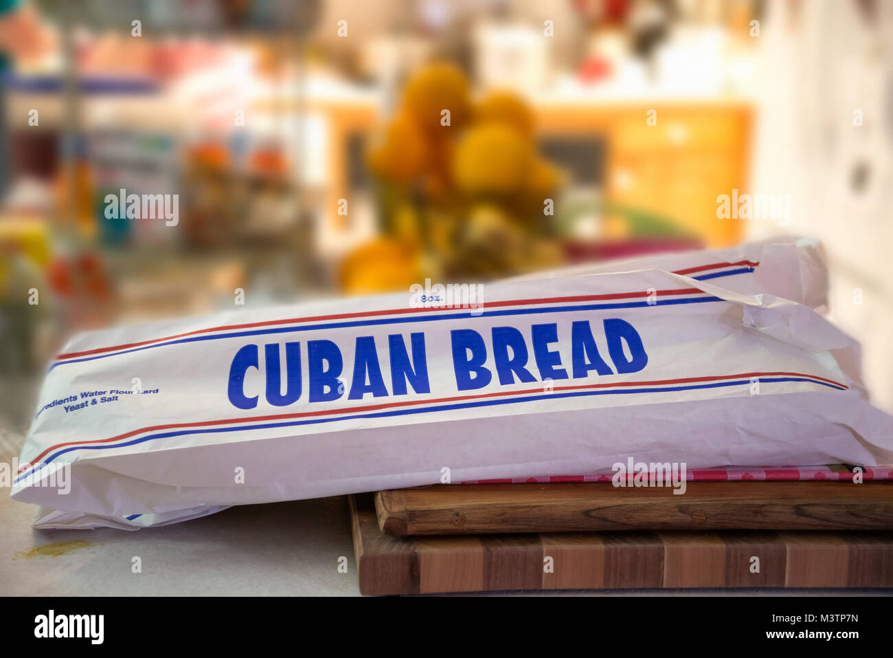 Bag of Cuban Bread atop a cutting board in a kitchen. Stock Photo