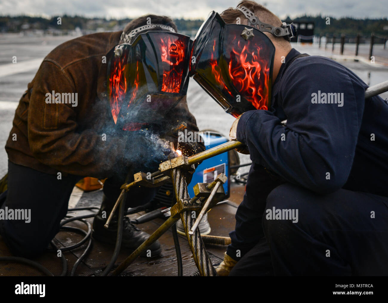 NAVAL BASE KITSAP-BREMERTON, Wash. (Oct. 2, 2016) - Seaman Chase Ethridge (right), a native of Katy, Texas, steadies an arresting cable while Petty Officer 3rd Class Gabriel Moreno, a native of Huntington Beach, Calif., welds during a reweave of the arresting gear on board USS Nimitz (CVN 68). Nimitz is currently undergoing an extended planned incremental maintenance availability at Puget Sound Naval Shipyard and Intermediate Maintenance Facility where the ship is receiving scheduled maintenance and upgrades. (U.S. Navy photo by Petty Officer 3rd Class Samuel Bacon/Released) Sailors weld arres Stock Photo