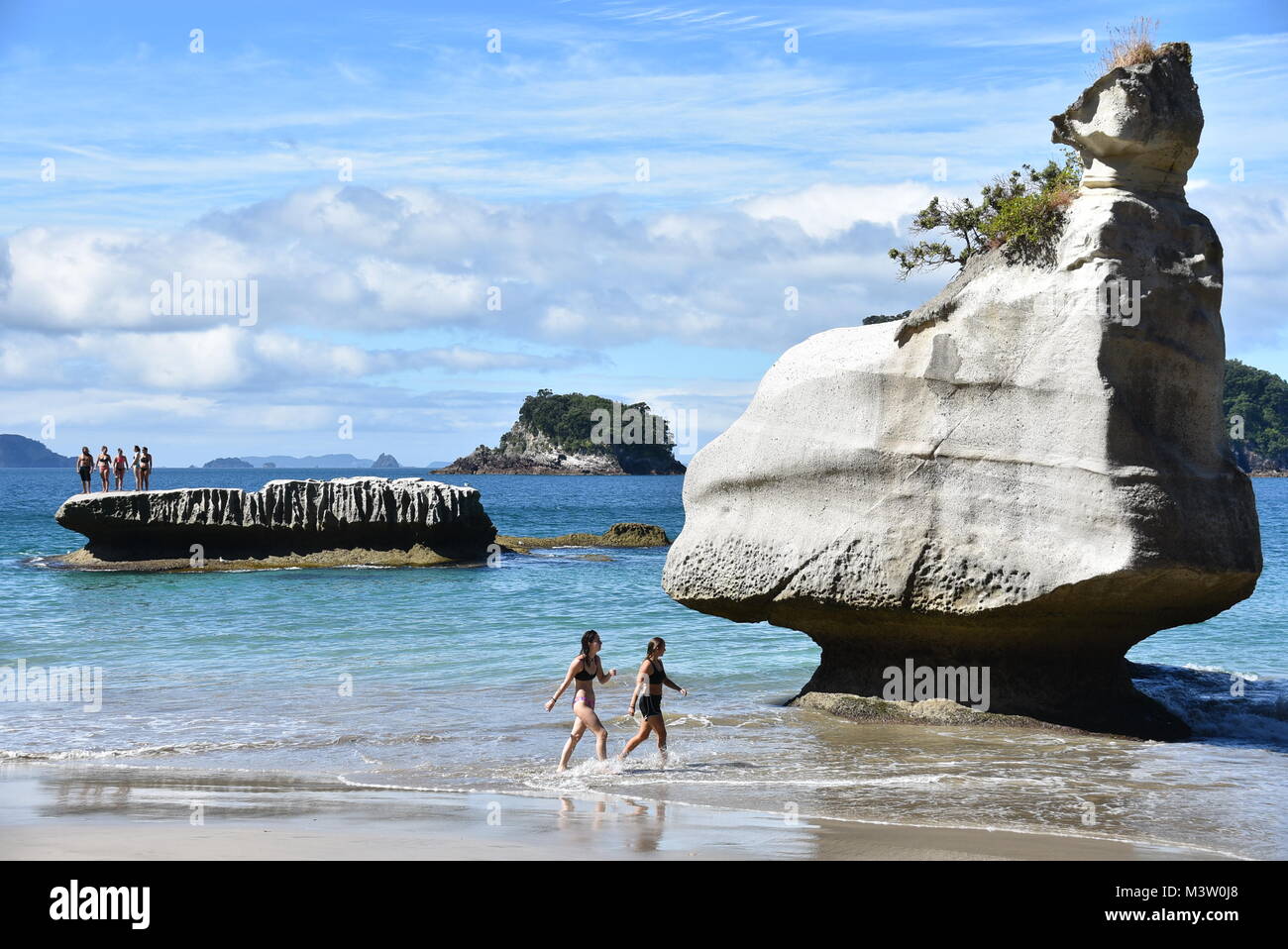 People walking on the beach and jumping from a cliff to the sea. Stock Photo
