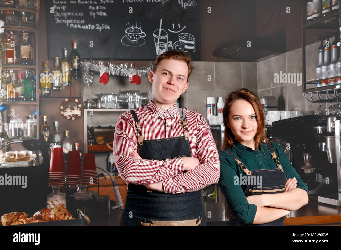 Couple of barista standing side by side in cafe. Handsome man and attractive woman are making coffee. Food and drink industry concept Stock Photo