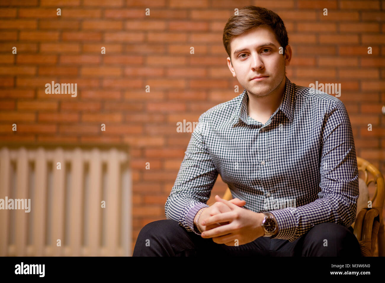 Smiling Young Man Leaning Against Brick Wall Stock Photo - Alamy