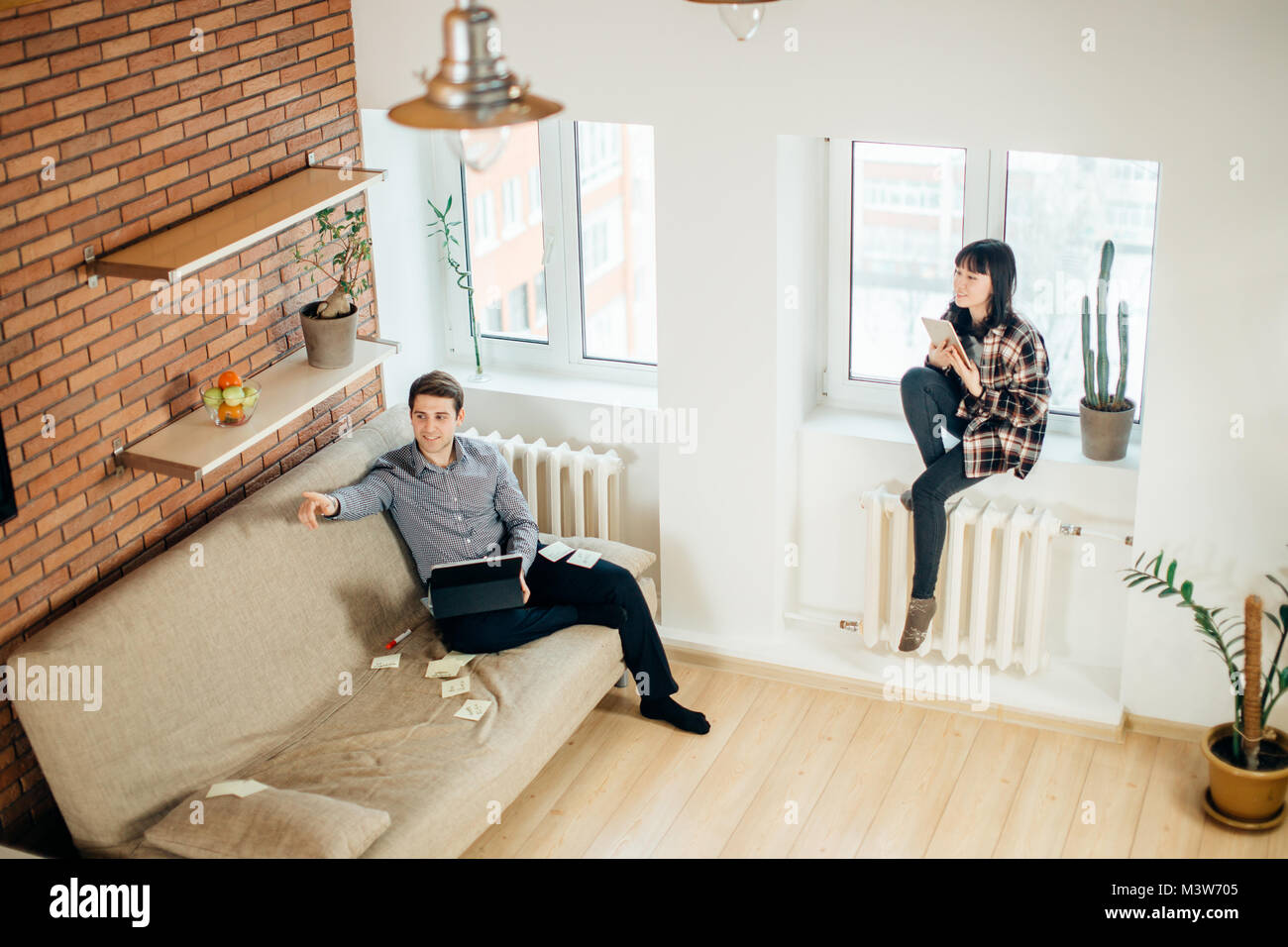 man and woman sitting back to back and doing their works Stock Photo