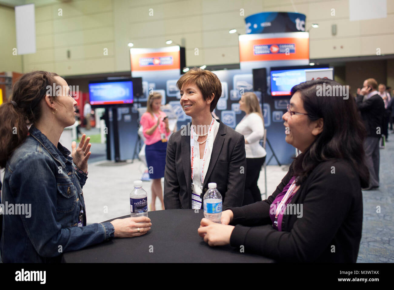 Canada Post Corporation's Marketing Manager Nadia Chegrinec, left, Director of Business Marketing Donna Reid and Manager of Marketing Research Angie Kwong speak during a break at the Art of Marketing conference in Toronto, Ontario, Canada on Wednesday, June 05, 2013. The conference hosted speakers and vendors geared towards the new age of marketing, including keynote speaker Biz Stone, co-founder and creative director of Twitter. Stock Photo