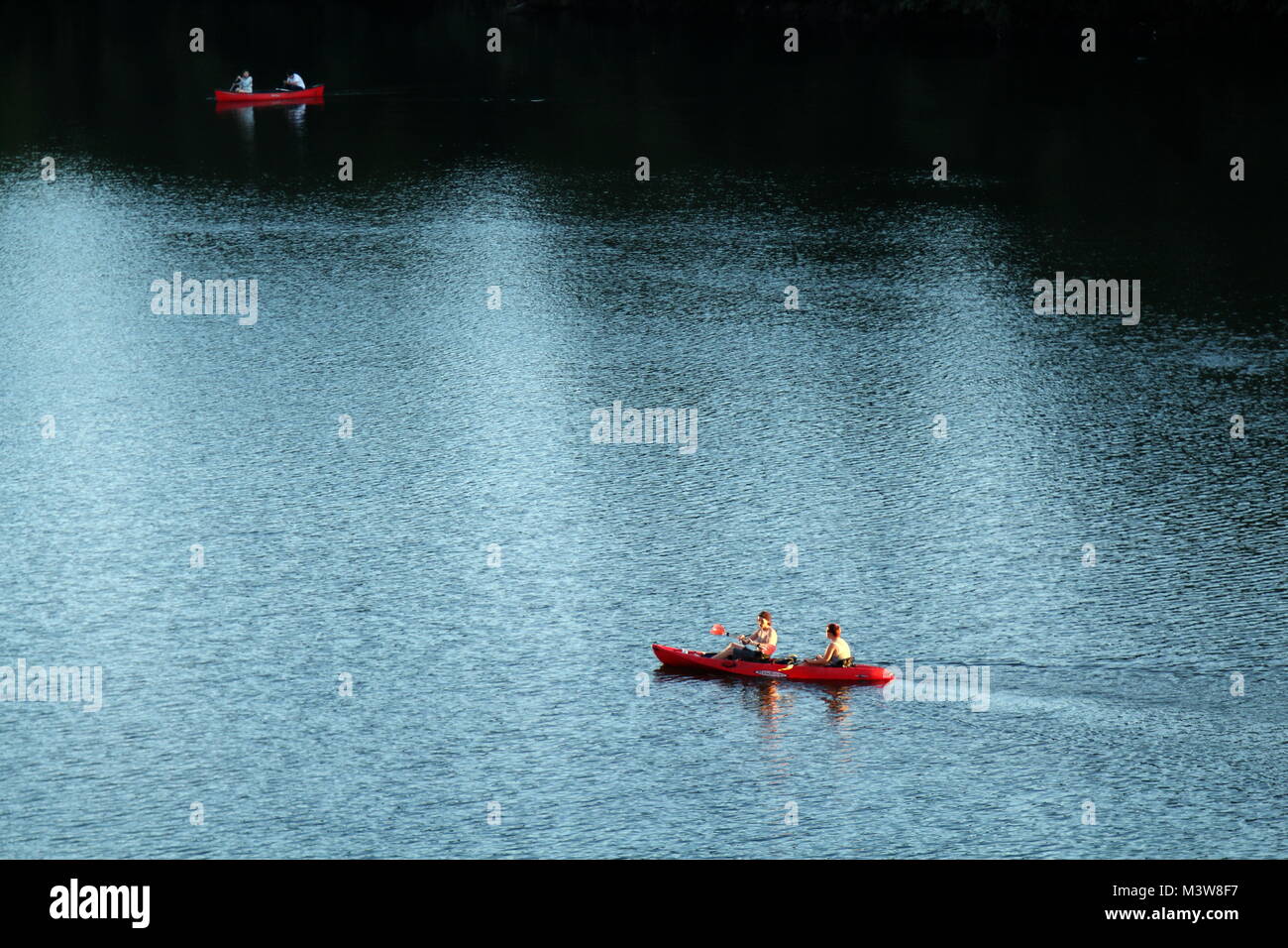 AUSTIN, TEXAS - SEPTEMBER 30, 2017: Two red kayaks navigating light and dark waters of Colorado river as seen from Congress bridge in Austin, Texas. Stock Photo