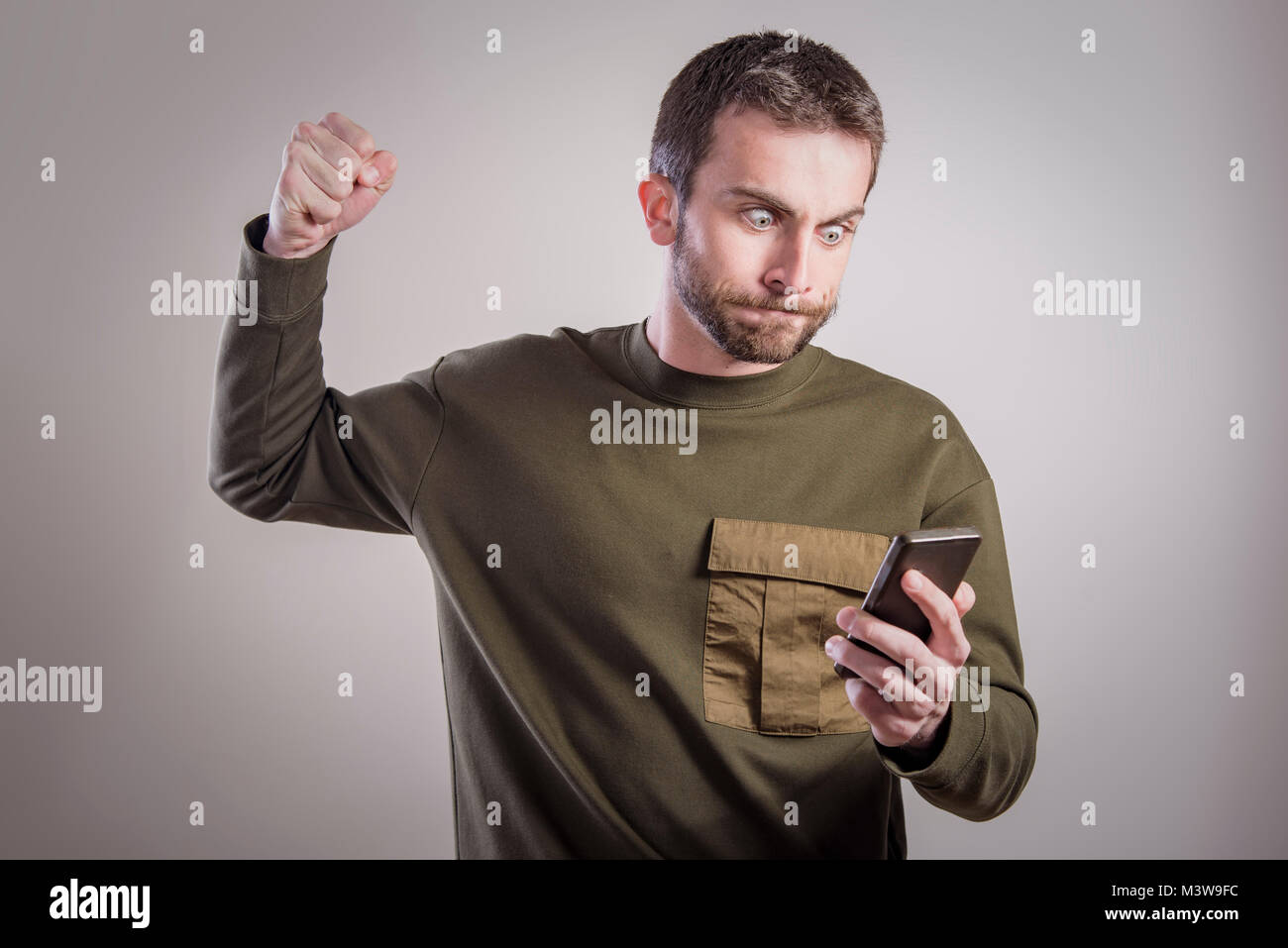 Man angry at his phone, outraged and enraged Stock Photo