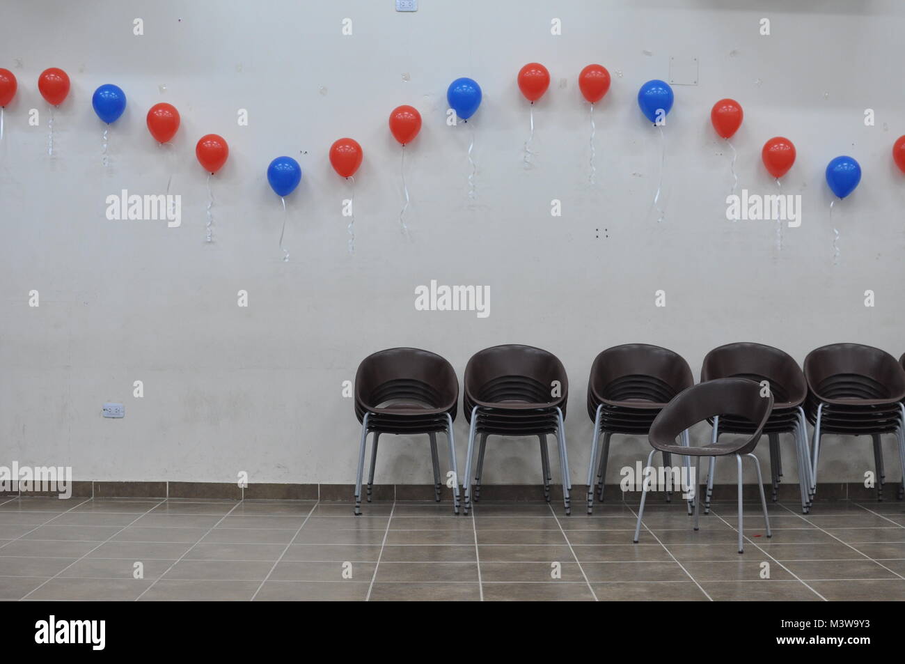 Stacks of chairs and balloons on the wall after a party celebration Stock Photo