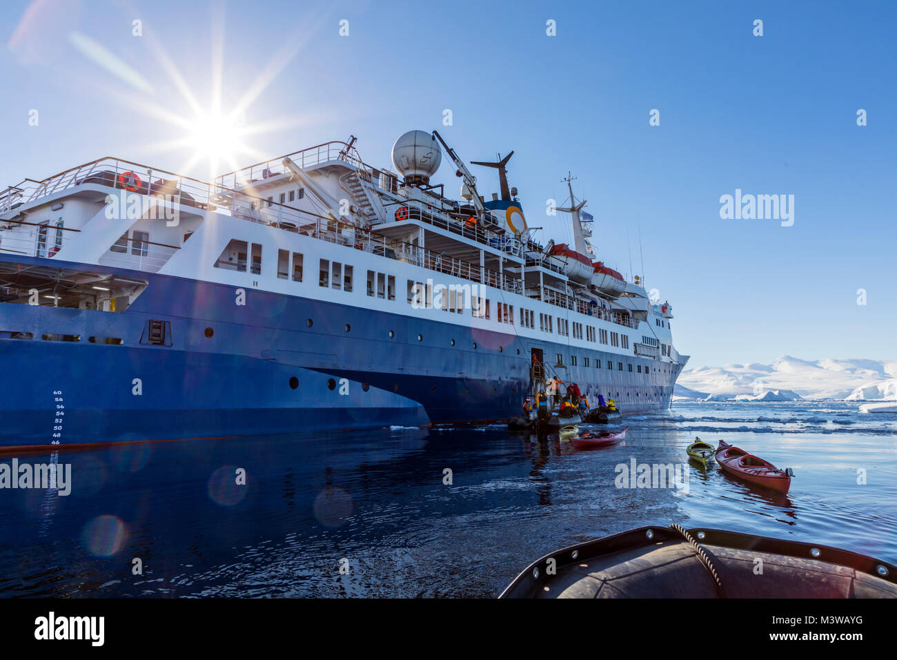Guides in Zodiacs tow empty kayaks used to explore snow covered Antarctica back to the Ocean Adventurer; cruise ship; Nansen Island Stock Photo
