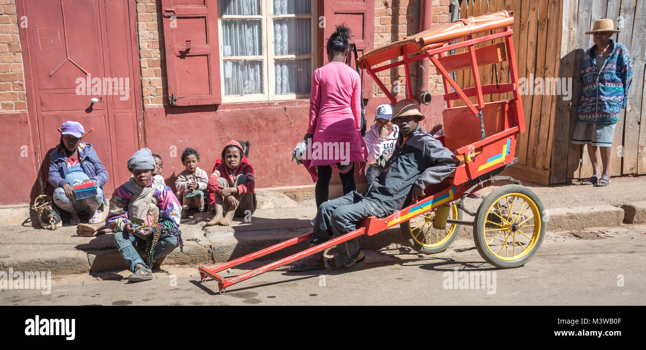 Rickshaw Driver and Family Sitting by Road, Antsirabe, Madagascar Stock Photo