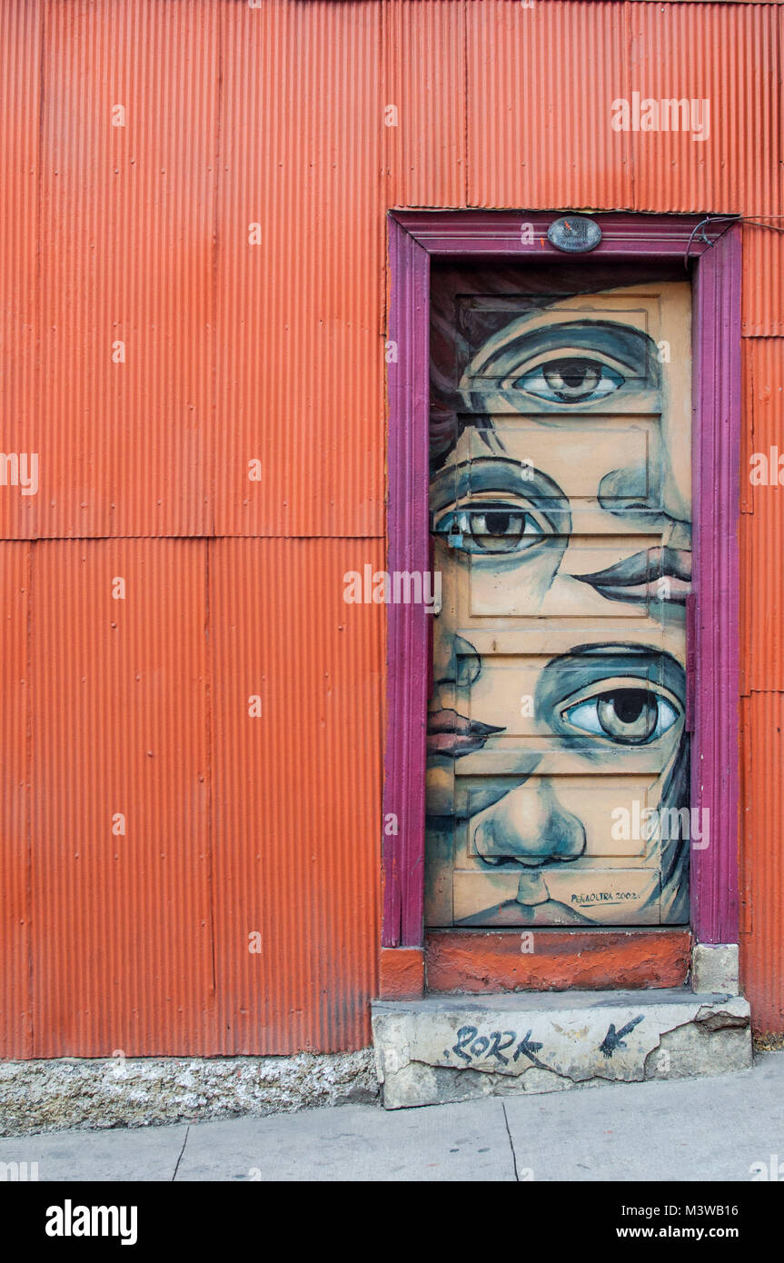 Human faces painted on the door of a colorful house made from corrugated iron in Valparaiso, Chile Stock Photo