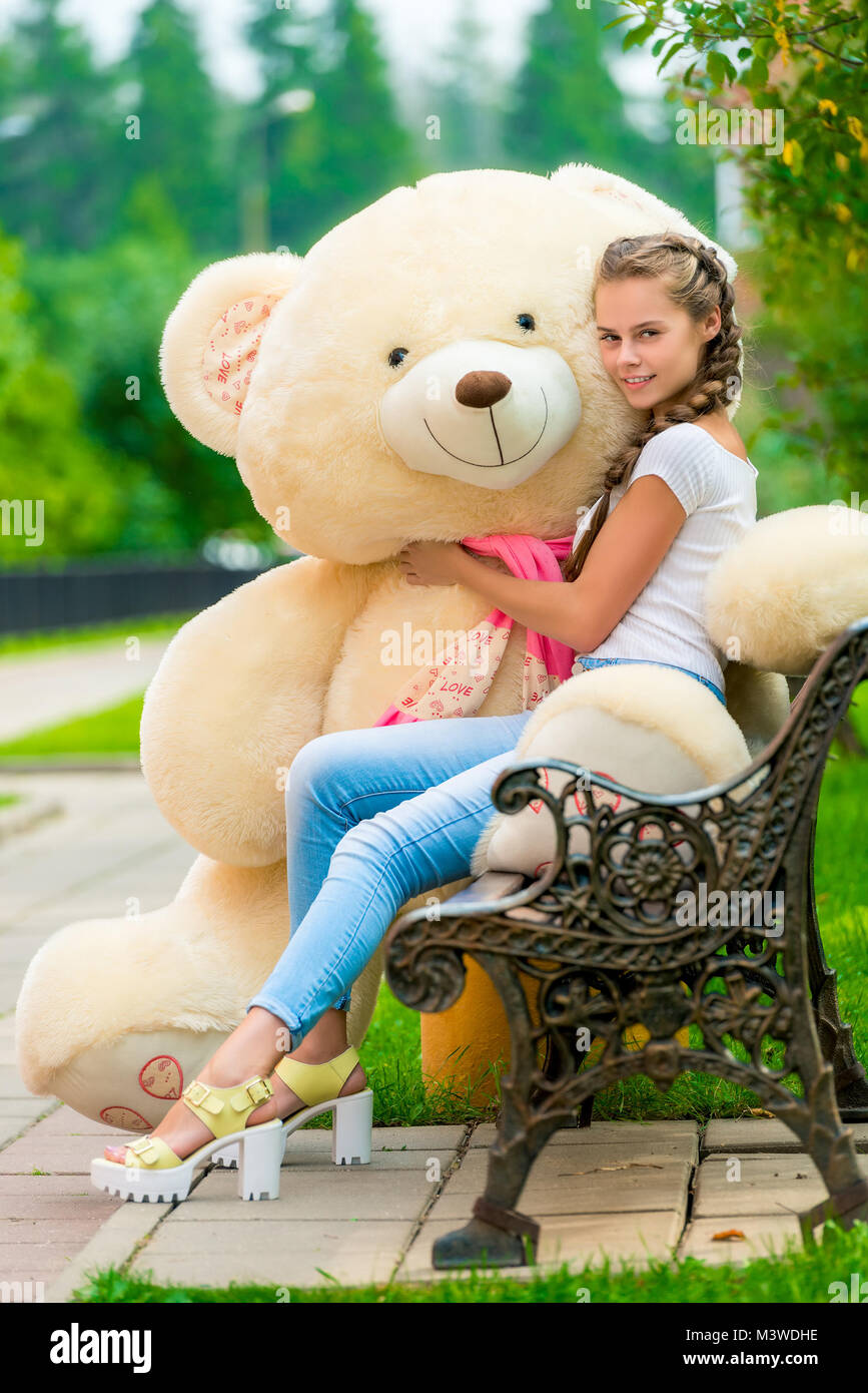 charming stylish girl on a bench with a teddy bear in the park Stock ...