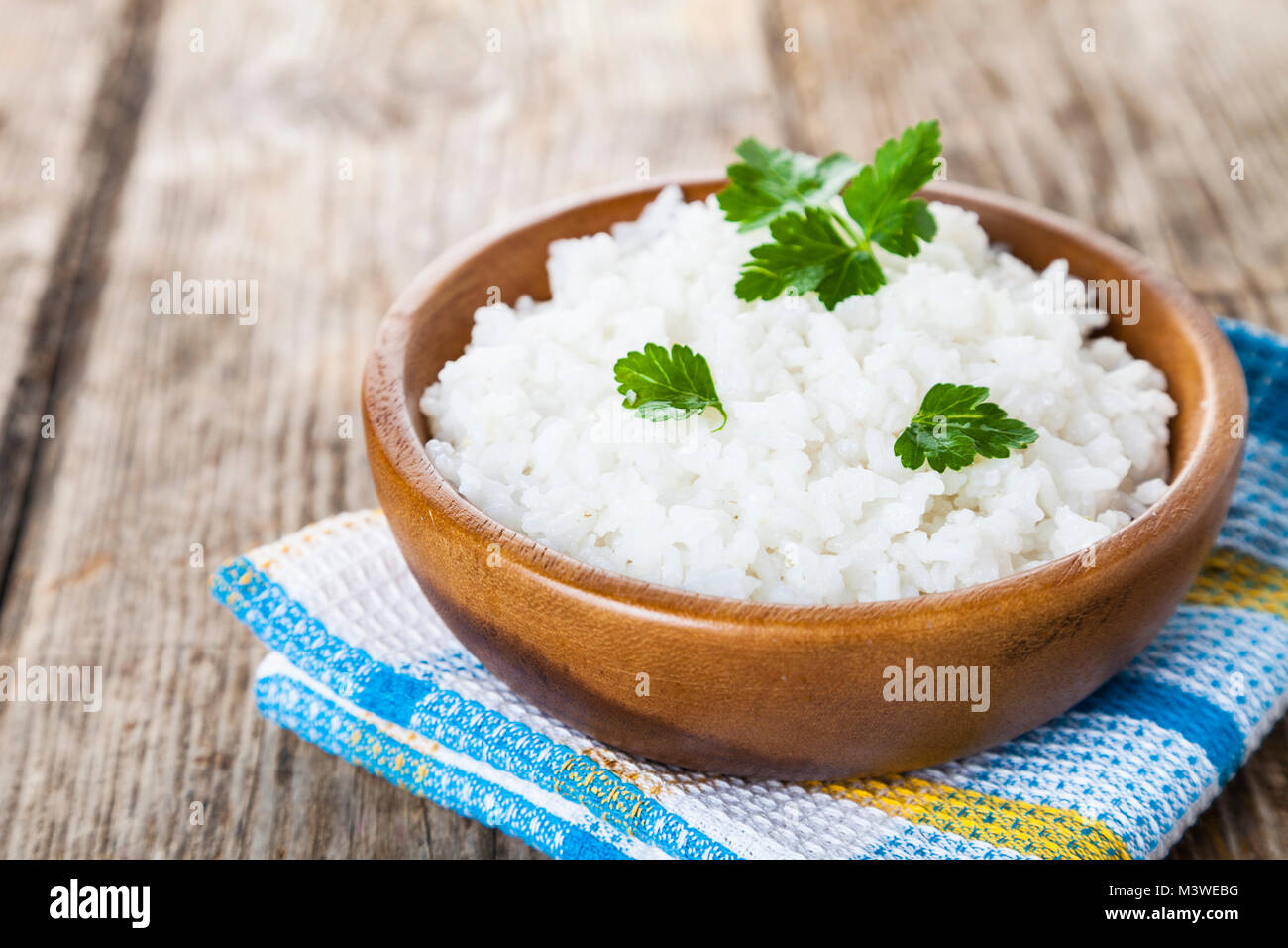Boiled rice in a wooden bowl on the table. Delicious vegetarian dinner. Stock Photo